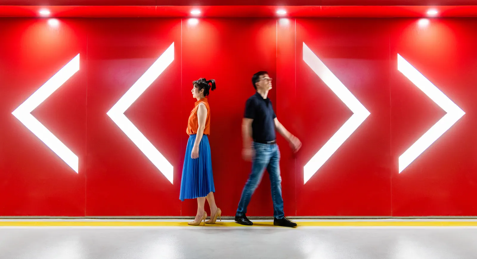 People walking through a red interior with illuminated directional arrows